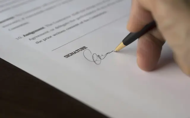 Mano firmando un documento con un lápiz de mina